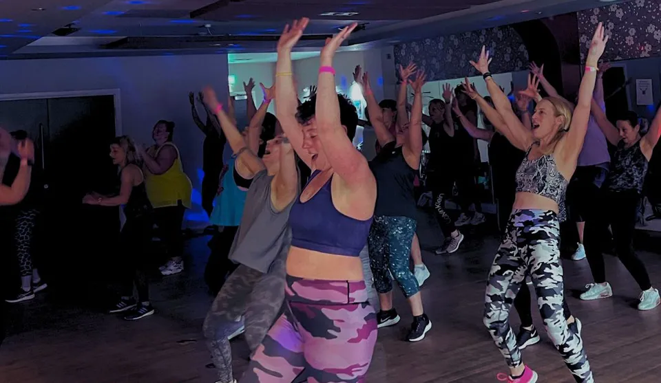 A BOOSTfit group dancing with their arms raised