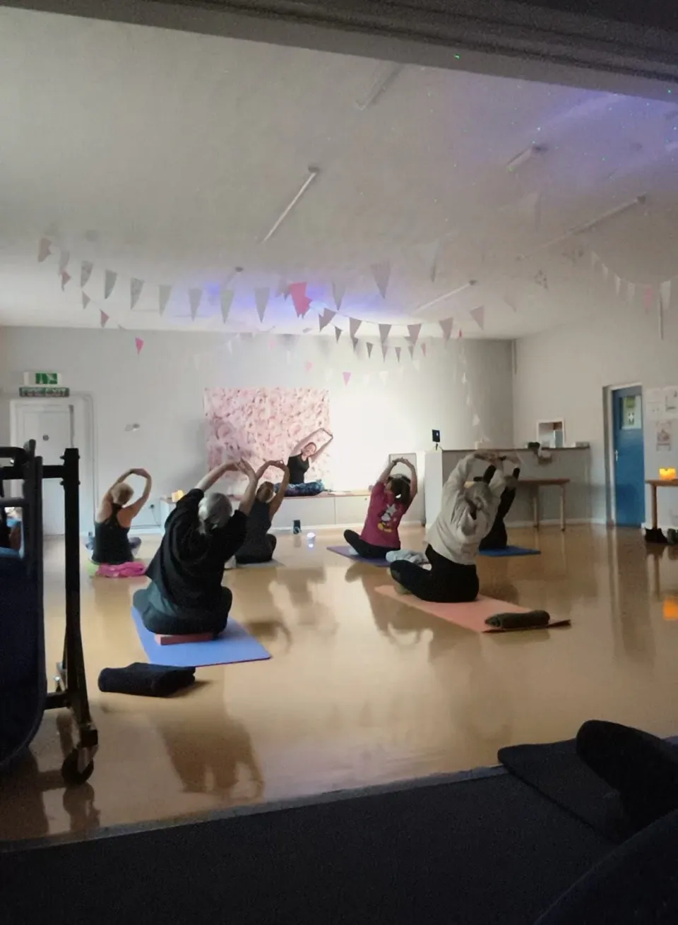 Liv leading a gentle seated stretch with a group on their mats
